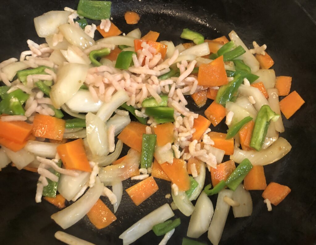 フライパンで焼きそばの具を炒めている